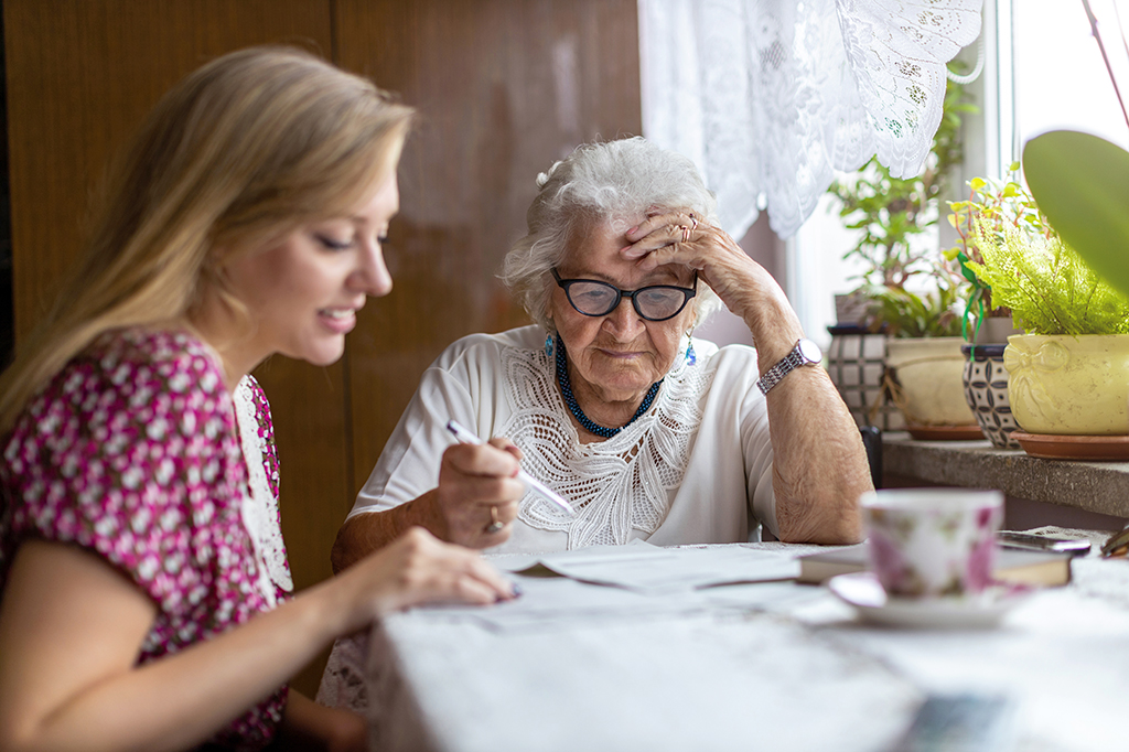 Photo of young woman helping elderly grandmother with paperwork